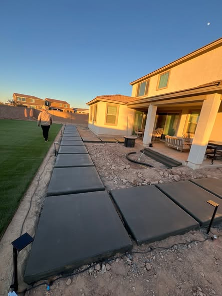Dark concrete pad walkway leading to a covered patio